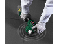 Mains gantées utilisant un outil électrique pour jointoyer les carreaux, avec batterie à côté.