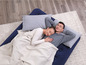 Un couple dort sur un matelas pneumatique avec des couvertures et des oreillers.