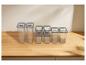 Contenants alimentaires transparents sur table en bois, de différentes tailles avec couvercles gris.