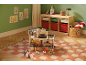 Chambre d'enfant avec maison de poupée, jouets, tapis et meubles de rangement.