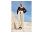 Modèle portant un cardigan, un pantalon et des sandales sur une plage.