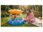 Mère et bébé jouant dans une pataugeoire gonflable avec parasol dans un jardin.