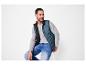 Homme portant une veste sans manches bleue, un t-shirt gris à manches longues et un jean.