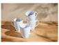 Ensemble de quatre mugs blancs sur une table en bois.