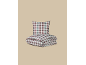 Parure de lit à carreaux avec oreiller et couette pliée sur fond beige.