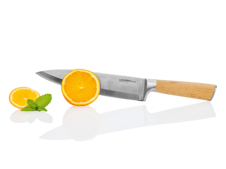 Un couteau de cuisine Livarno Home avec manche en bois, reposant sur une moitié d'orange.