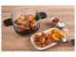 Friteuse à air en verre avec ailes de poulet et quartiers de pommes de terre, ketchup et sel sur une table en bois.
