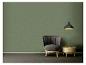 Mur vert avec un fauteuil gris, une table d'appoint en bois et une suspension noire.