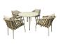 Ensemble de jardin avec table ronde et quatre chaises tressées avec coussins.
