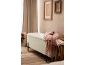 Banc rembourré avec une couverture rose dans un cadre douillet avec rideaux et tableaux.