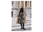 Femme en manteau beige, pull noir et jupe à imprimé zèbre.