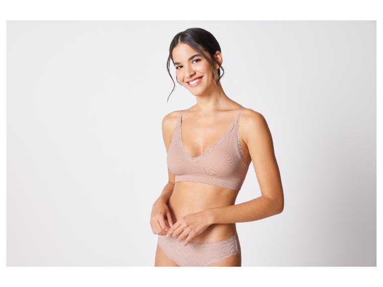 Une femme porte un soutien-gorge et une culotte beige en dentelle.
