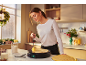 Femme préparant des crêpes sur une crêpière dans une cuisine décorée pour Noël.