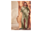 Une femme pose avec un ensemble pantalon et chemise vert clair et des sandales noires.