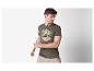 Modèle portant un t-shirt vert olive avec un imprimé plage.