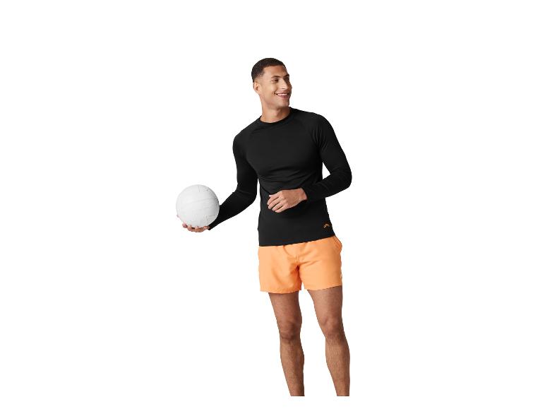 Homme en t-shirt noir à manches longues et short orange, tenant un ballon de volley-ball.