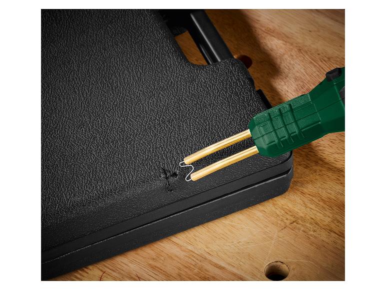 Outil de soudage plastique à poignée verte réparant une surface noire texturée.