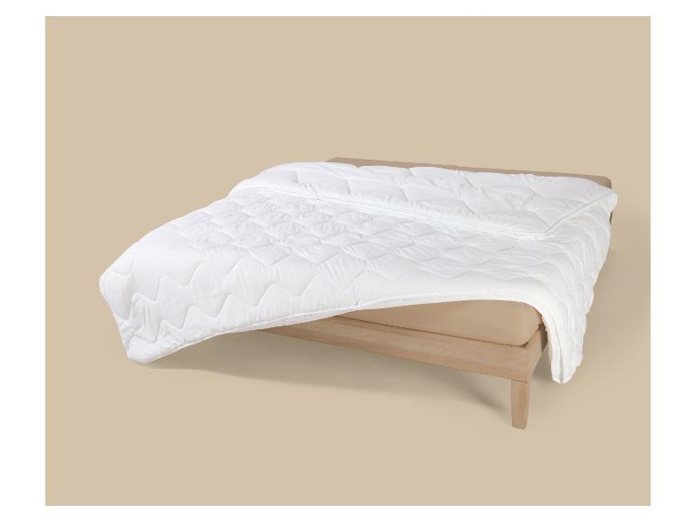 Couette blanche matelassée sur un lit à cadre en bois