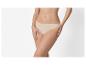 Femme en culotte couleur chair, mains sur les cuisses.