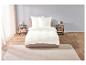 Draps blancs sur un lit avec deux tables de chevet.