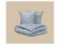 Parure de lit bleue avec motif de branches fleuries blanches.