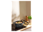 Une casserole noire avec des légumes cuits sur une plaque à induction.