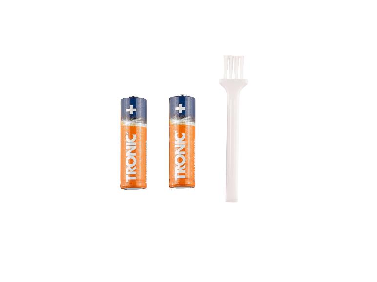 Deux piles et une brosse de nettoyage blanche sur fond blanc.