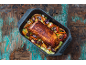 Rôti de porc cuit au four avec des légumes dans un plat sur une table en bois