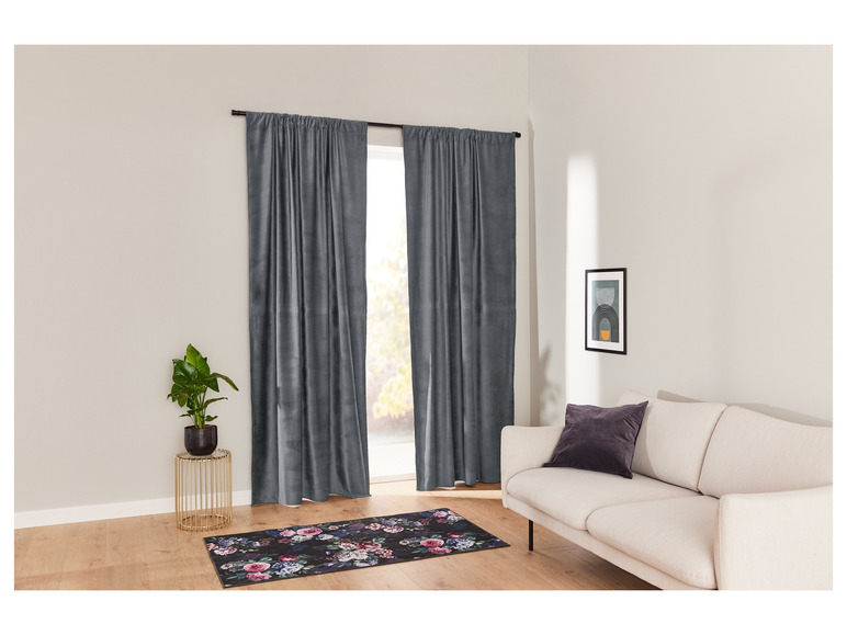 Des rideaux gris avec un tapis à fleurs noires dans un salon.