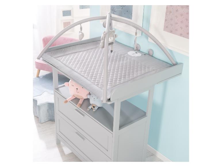Table à langer grise avec matelas matelassé, jouets suspendus et tiroirs.