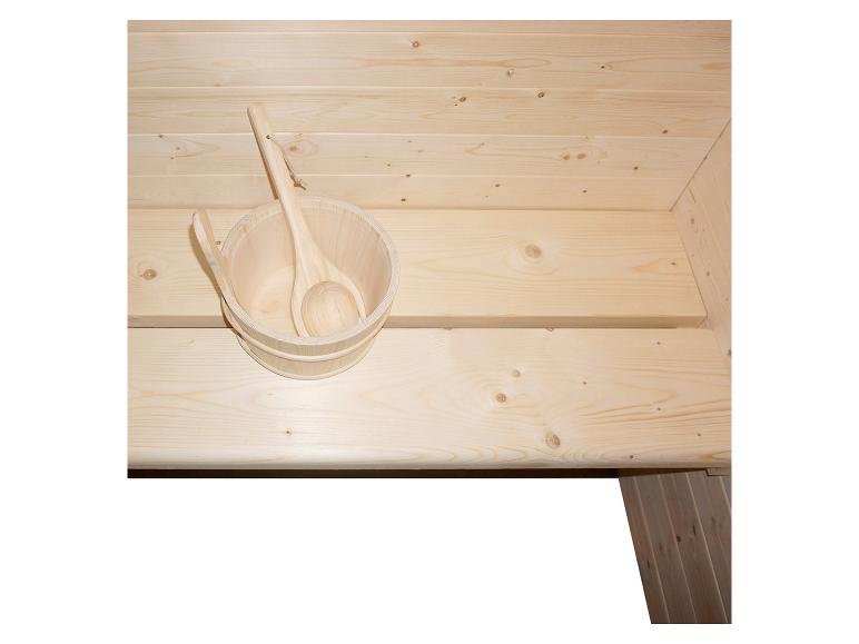 Seau de sauna en bois avec louche sur un banc en bois.