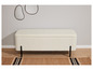 Un banc blanc en fourrure avec des pieds noirs sur un tapis à rayures noires.