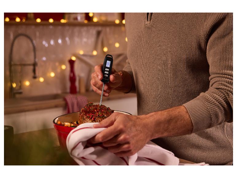 Une personne mesure la température d'un rôti avec un thermomètre à viande numérique dans une cuisine.