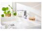 Robinetterie moderne, lavabo blanc et brosse à récurer en bois.