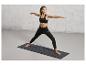 Une femme fait du yoga sur un tapis de yoga noir à imprimé léopard de la marque 'Ettesport'.