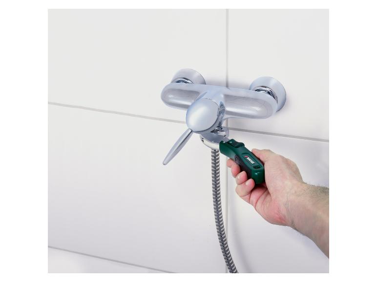 Une main utilise une clé dynamométrique pour serrer un robinet de douche.
