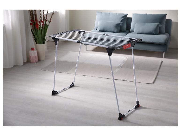 Séchoir à linge pliable dans un salon moderne avec un canapé et de la décoration.