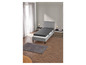 Un lit gris avec un matelas sur un sol en bois.