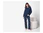 Une femme en pyjama bleu marine à étoiles blanches, debout à côté d'une chaise blanche.