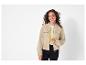 Une femme porte une veste bomber beige avec un t-shirt blanc en dessous.