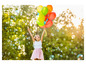 Une fille tient un bouquet de ballons et se tient dans un champ rempli de bulles de savon.
