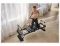 Femme faisant du pilates sur un reformer, vêtue d'un haut de sport et d'un legging.