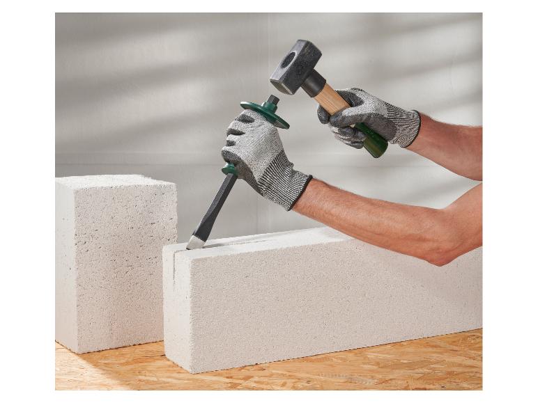Mains gantées utilisant un marteau et un ciseau sur des blocs de béton cellulaire.