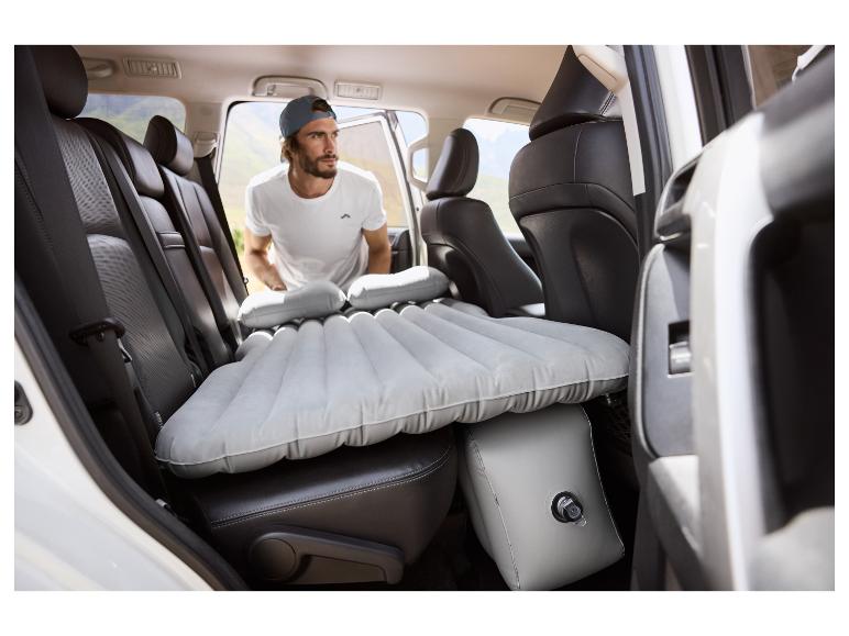 Homme dans une voiture avec un matelas gonflable et des oreillers.