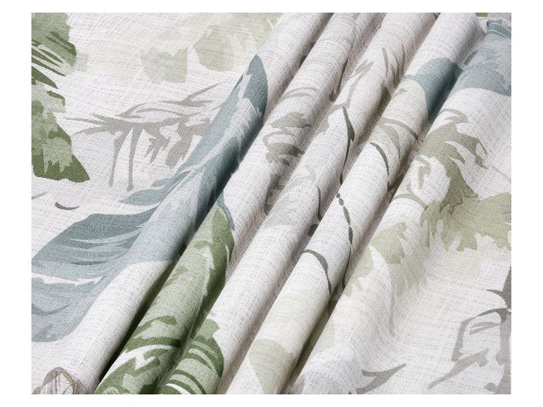 Gros plan d'un tissu blanc avec des motifs de feuilles tropicales vertes et grises, drapé en plis doux.