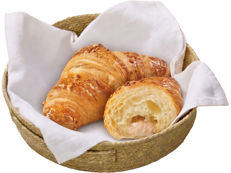Deux croissants, un entier et un coupé pour montrer la garniture, dans un panier tressé avec un tissu blanc.