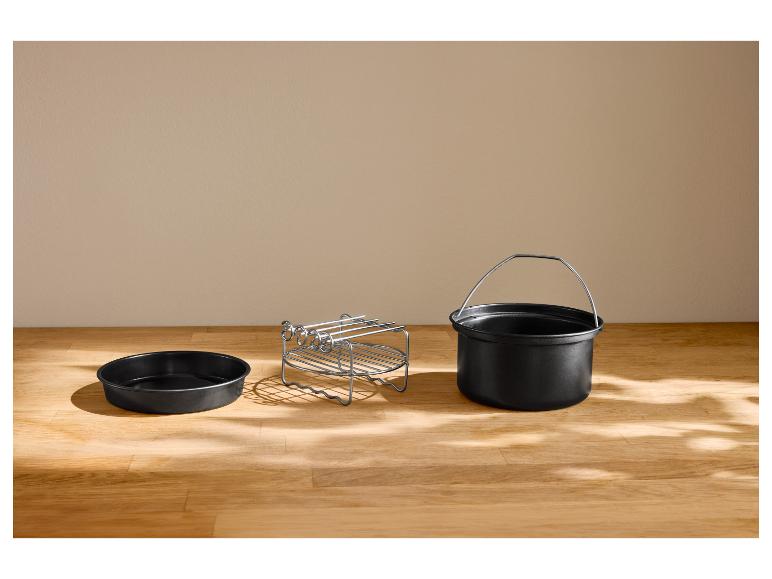 Plat rond, grille et pot avec poignée pour friteuse à air sur une table en bois.
