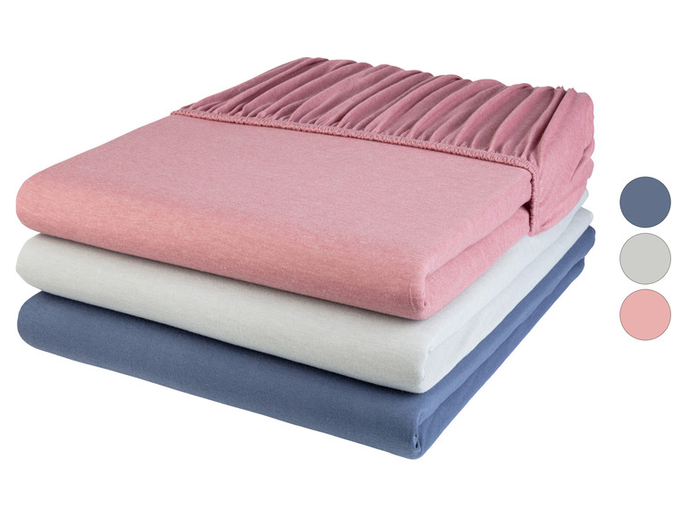 Une pile de draps-housses rose, gris et bleu.