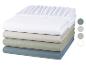 Un drap housse blanc, un beige, un vert et un bleu empilés.