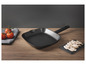Une poêle à griller noire sur une table en bois avec des champignons en tranches.